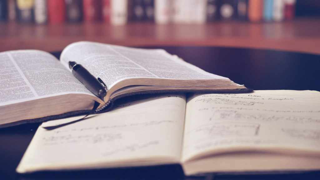 Journaling about books with an open book and a pen on a table.